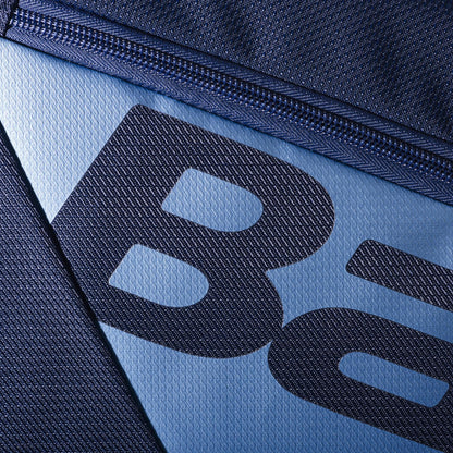 A close-up of navy blue textured fabric with a zipper, displaying partial letters "B" and "a." The design features diagonal lines forming a geometric pattern, perfect for the large capacity Babolat RH12 Pure Drive Gen11 12 Racket Tennis Bag.