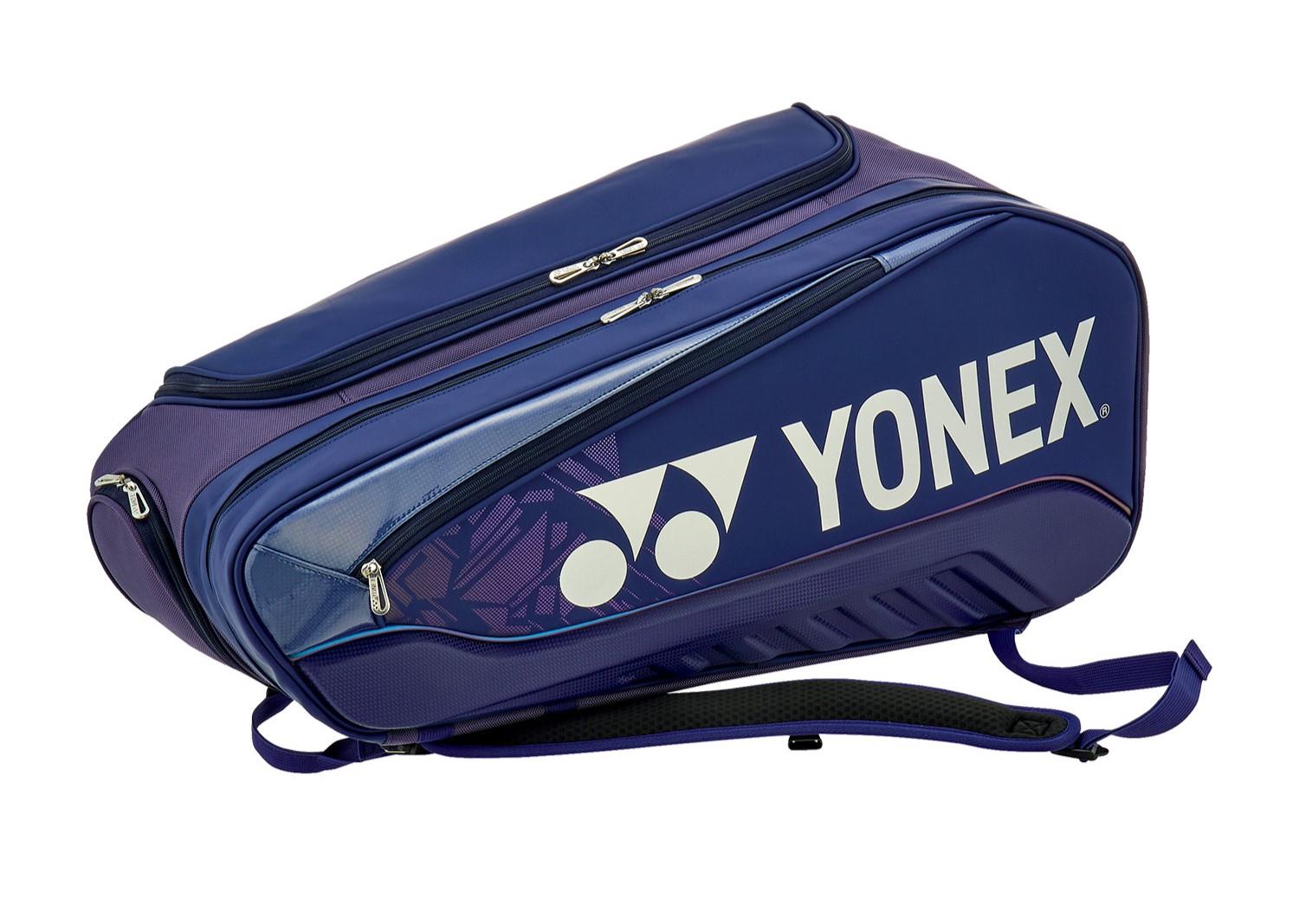 A Yonex 02526EX Expert 6 Racket Tennis Bag in navy blue lies on its side, featuring zippered compartments, two shoulder straps, a removable racket compartment for convenience, and prominently displaying the white Yonex logo on the side.