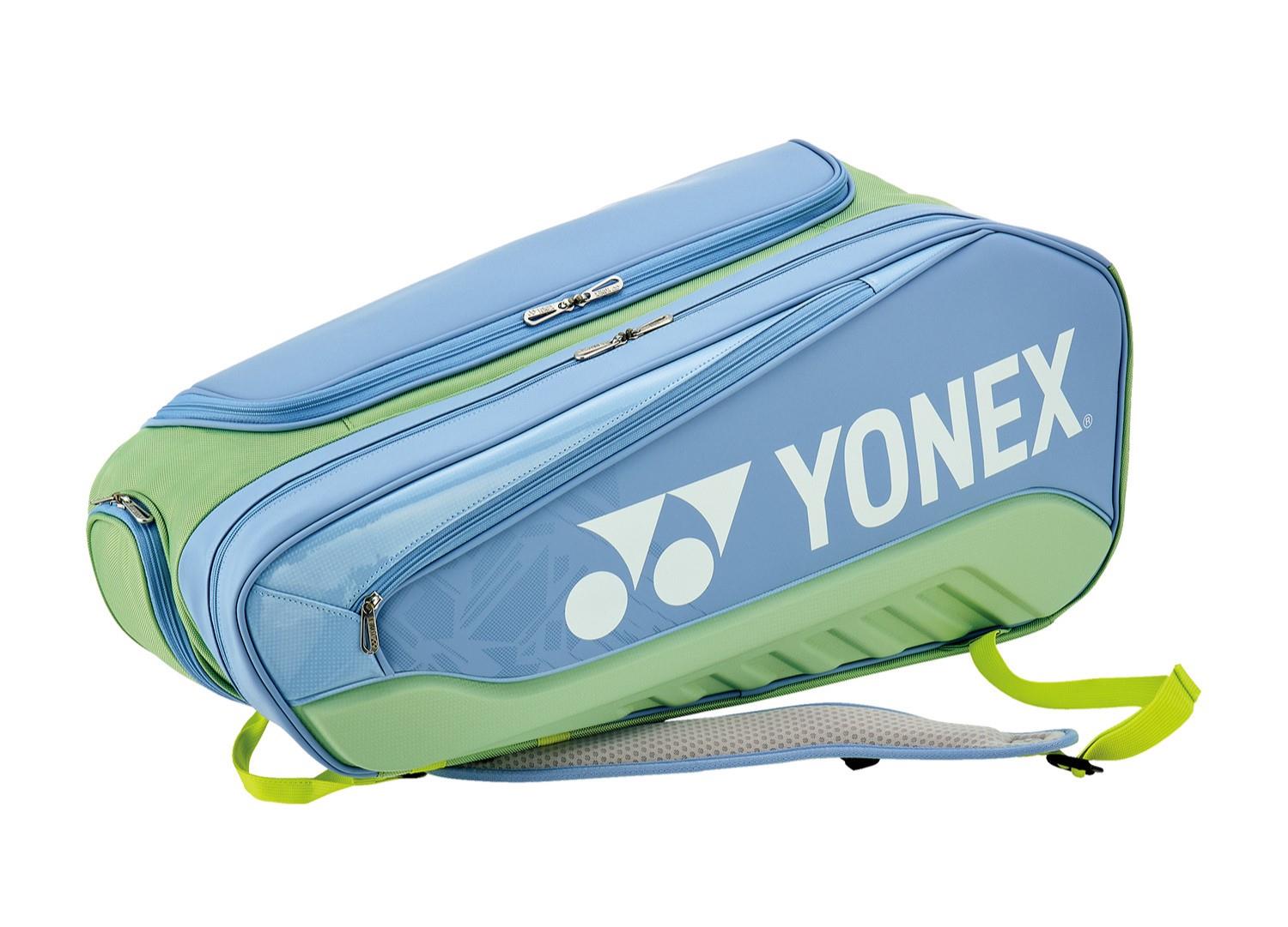 The Yonex 02526EX Expert 6 Racket Tennis Bag in Smoke Blue features a large zippered compartment, two smaller pockets, padded shoulder straps, a yellow carrying strap, and a removable racket divider. The bag also prominently displays the Yonex logo.