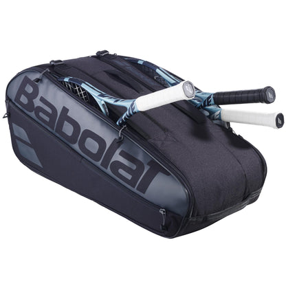 A black Babolat Court L 9 Racket Tennis Bag reveals two rackets with handles protruding, showcasing the large logo on the side. This versatile bag by Babolat has multiple zippered compartments.