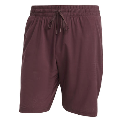 These Ruby ADIDAS Ergo Men's Tennis Shorts by adidas have an elastic waistband with a drawstring, are made from recycled materials, and offer lightweight comfort and flexibility. The subtle textured pattern enhances their style, making them perfect for on-court performance.