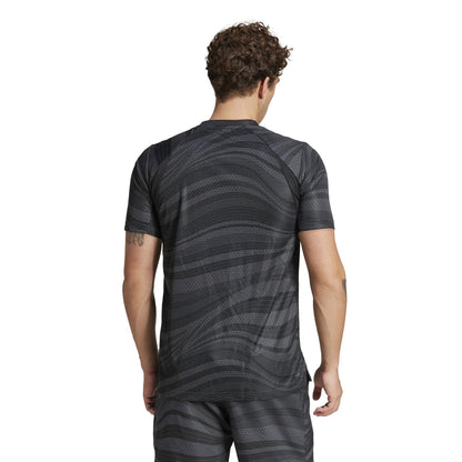 Seen from behind, someone with curly hair wears the ADIDAS Mens Club Graphic Tennis T-Shirt in black by adidas, crafted from recycled materials. The athletic shirt and matching shorts boast AEROREADY technology against a plain white background.