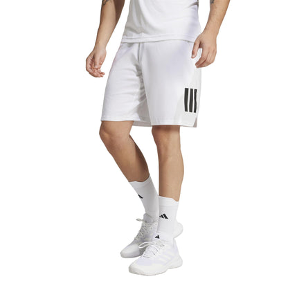 Someone is wearing adidas Men's 3 Stripe Tennis Shorts in white, featuring black stripes on one leg, paired with a white shirt, white sneakers, and white socks with black stripes against a plain white background.