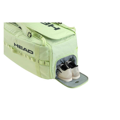 A light green HEAD Pro Duffle Tennis Bag L - LLAN prominently features the brand name "HEAD" and includes a zippered compartment, where a pair of white and black shoes are partially visible. It's ideal for storing gear like a tennis racket.