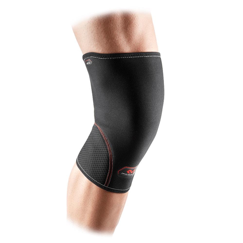 Close-up of a person wearing the McDavid Neoprene Knee Sleeve, featuring red stitching. This brace covers the knee and extends over part of the thigh and calf, offering thermal compression therapy. The white background enhances the contrast with the sleeve.