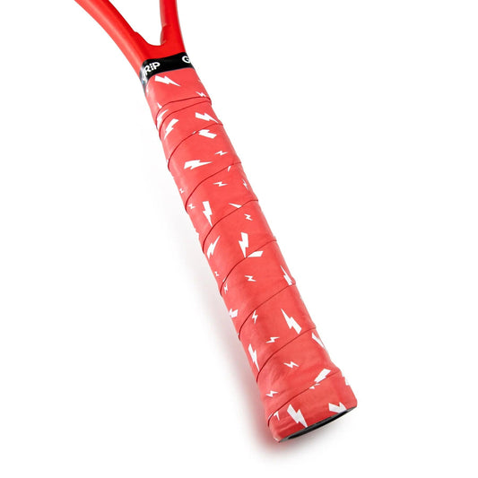 A close-up of the Get A Grip Charged Up Tennis Overgrip in red, displaying its premium quality and unique design adorned with small white lightning bolts, is wrapped around a racket handle. Positioned diagonally, the handle showcases the tennis overgrip's distinctive texture and pattern.